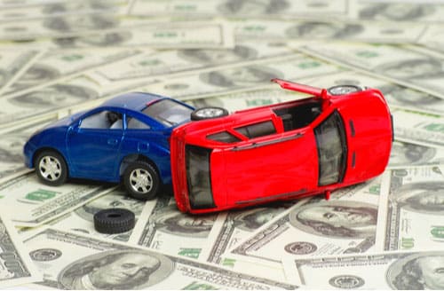 Toy cars crashed on pile of money, car accident claim concept