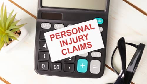 Calculator and card with words personal injury claims, personal injury lawsuit concept